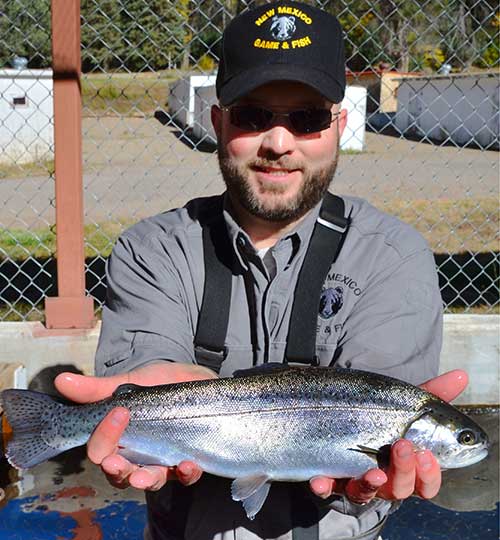 New Mexico Game & Fish hatchery manager holding a prize rainbow trout at Lisboa Springs