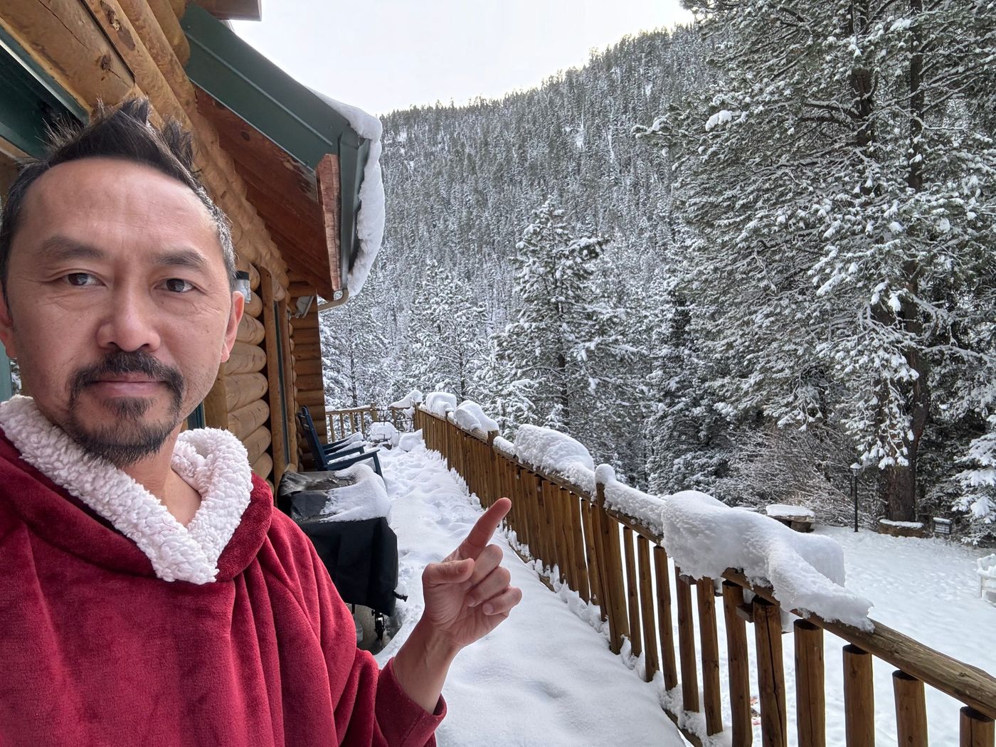 Duc on the snow-covered deck of the Ponderosa Main Lodge, pointing out over a snowy forested canyon
