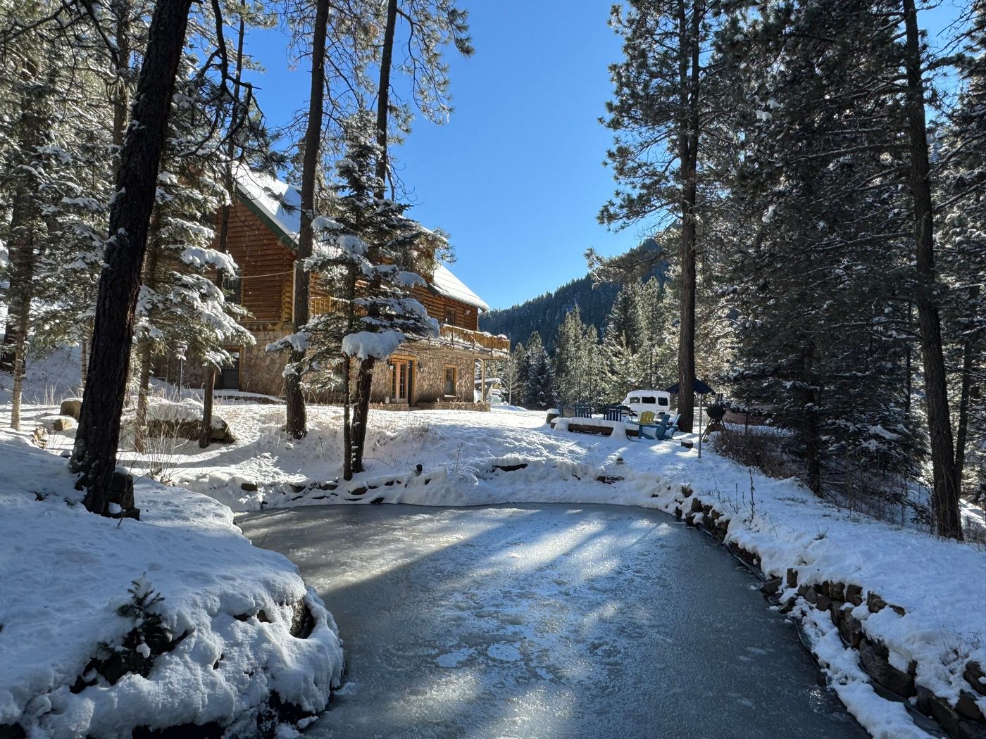 The Ponderosa Main Lodge in winter, with snow on the pines and the trout pond frozen over